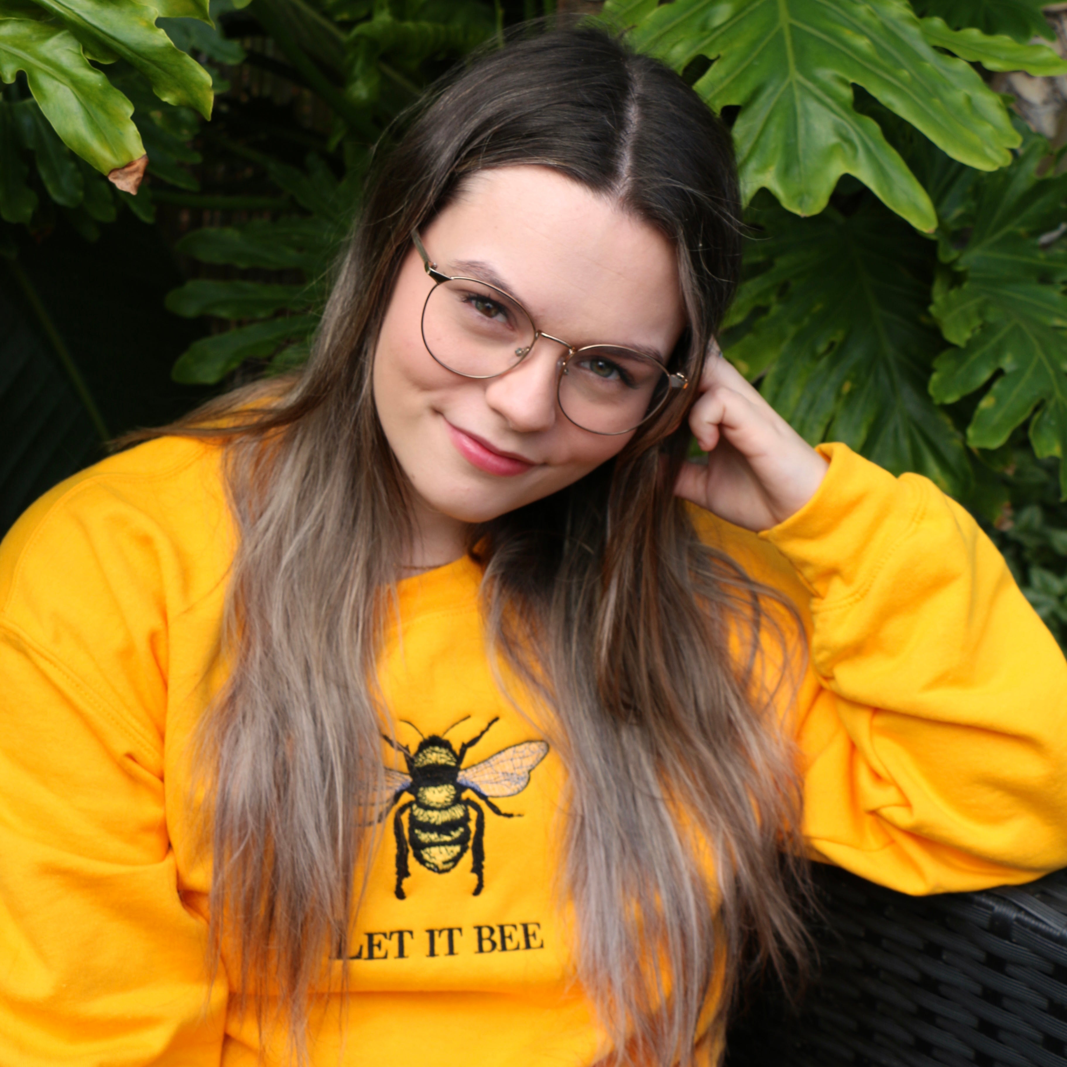 Photo lifestyle d'une jeune femme portant un crewneck jaune avec une abeille brodée dessus