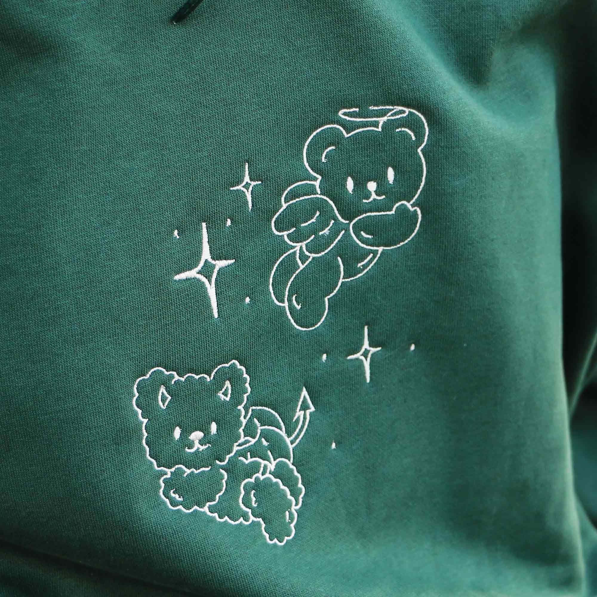 photo plan rapproché d'un coton ouaté vert foret avec une broderie de petits ourson blanc crème