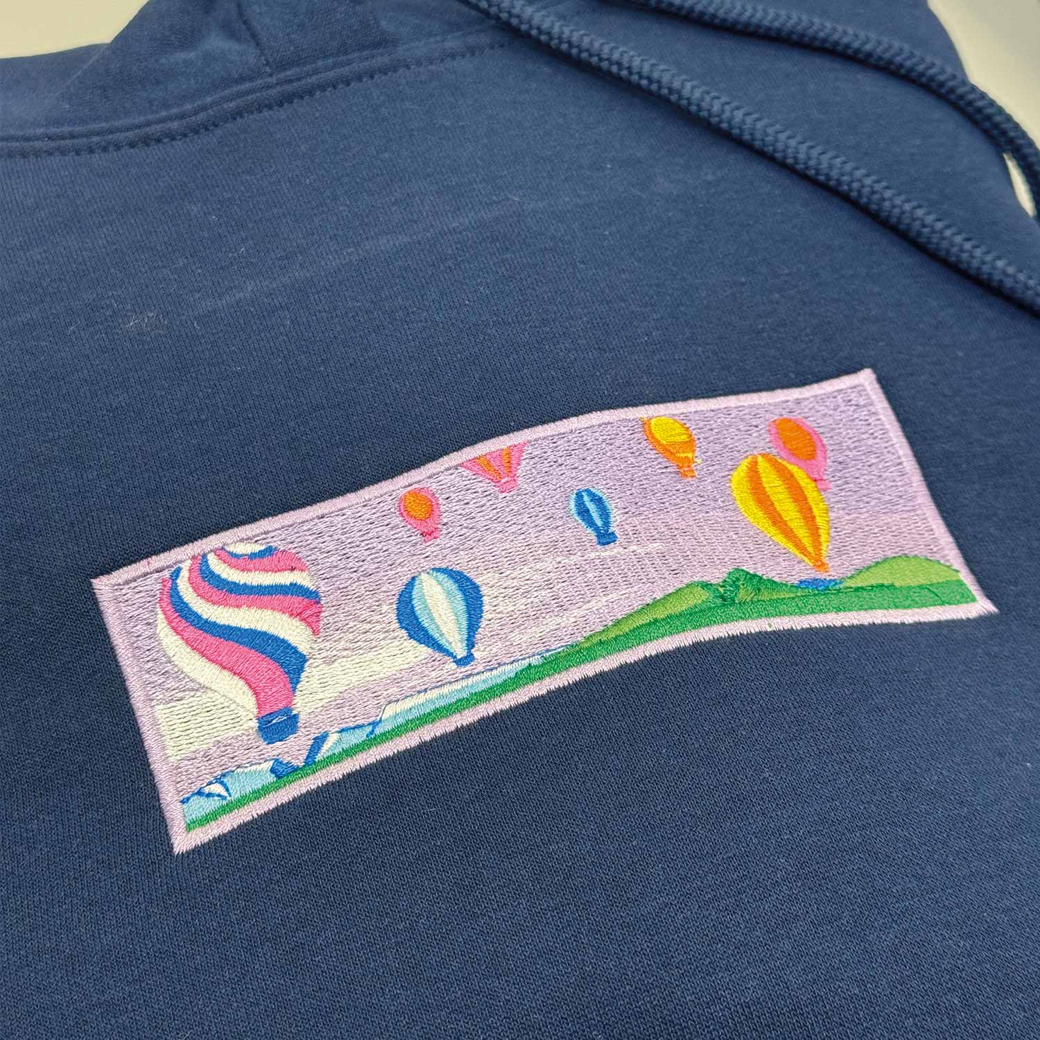 photo d'un plan rapproché d'un hoodie bleu marin avec un ciel rempli de montgolfières