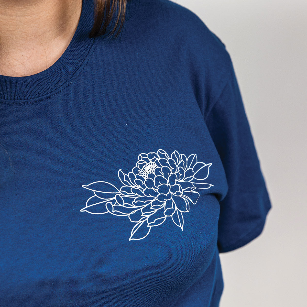 photo sur fond blanc d'une jeune femme de face portant un t-shirt bleu neptune avec un imprimé de lignage botanique minimaliste