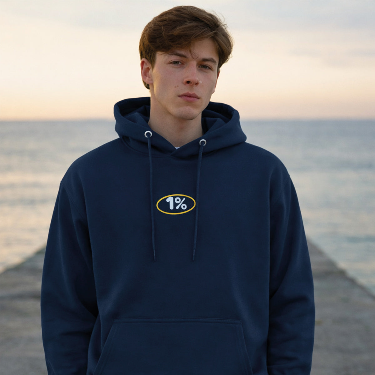 photo d'un jeune homme portant un coton ouaté bleu marin sur le bord de la mer au coucher de soleil