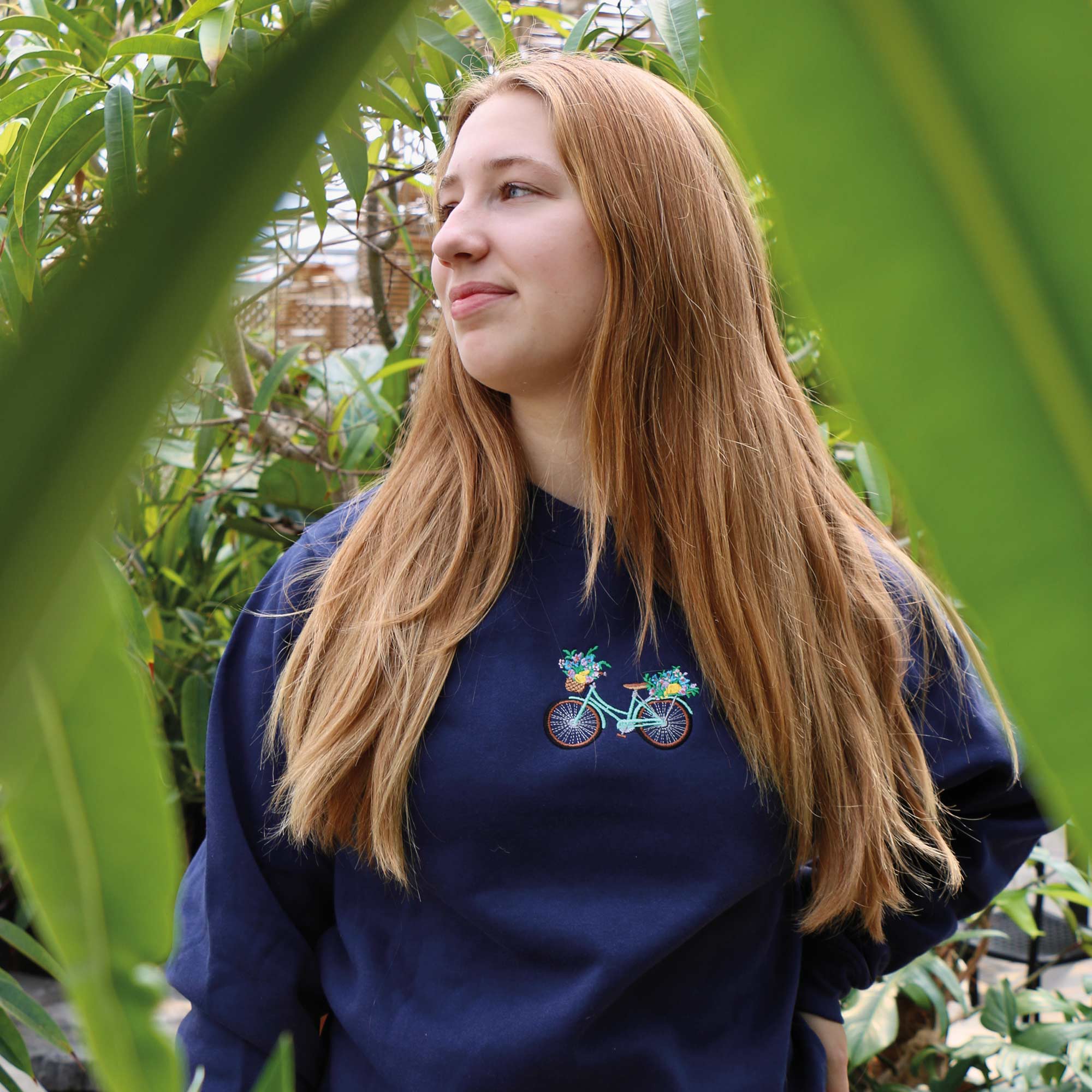 jeune femme blonde portant un crewneck bleu marin avec une broderie de vélo vintage fleuri
