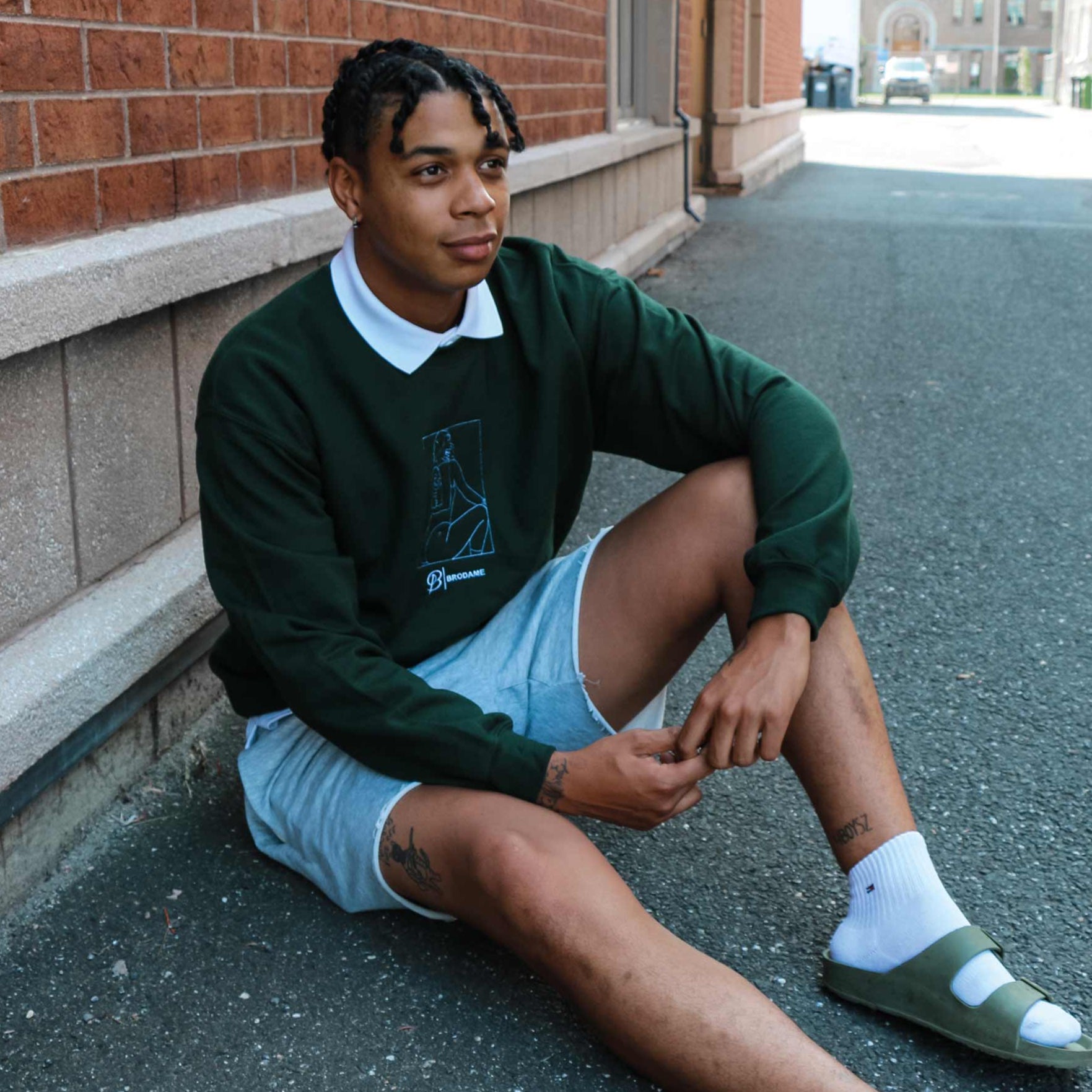 photo lifestyle d'un jeune homme portant un crewneck vert foret avec la silhouette coquine de sa copine brodée en blanc