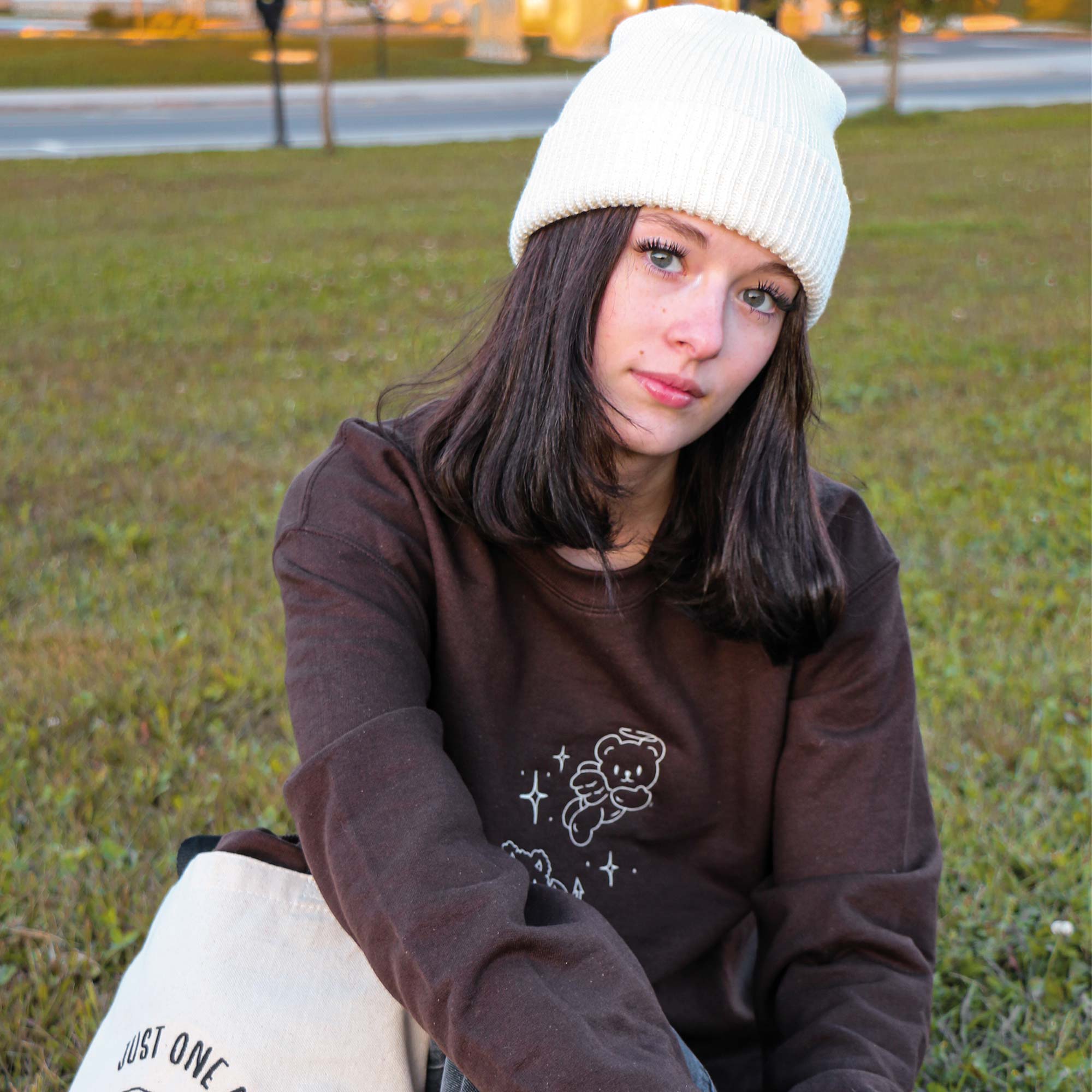 photo de jeune fille portant un crewneck brun avec une broderie d'oursons ange et demon en blanc avec une tuque de couleur blanc crème