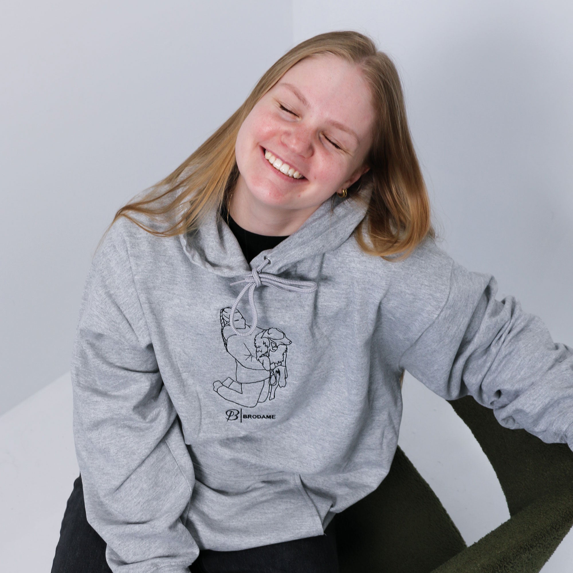 photo de studio d'une jeune femme blonde souriante portant un coton ouaté à capuchon gris pâle avec une broderie silhouette faite à partir d'une photo