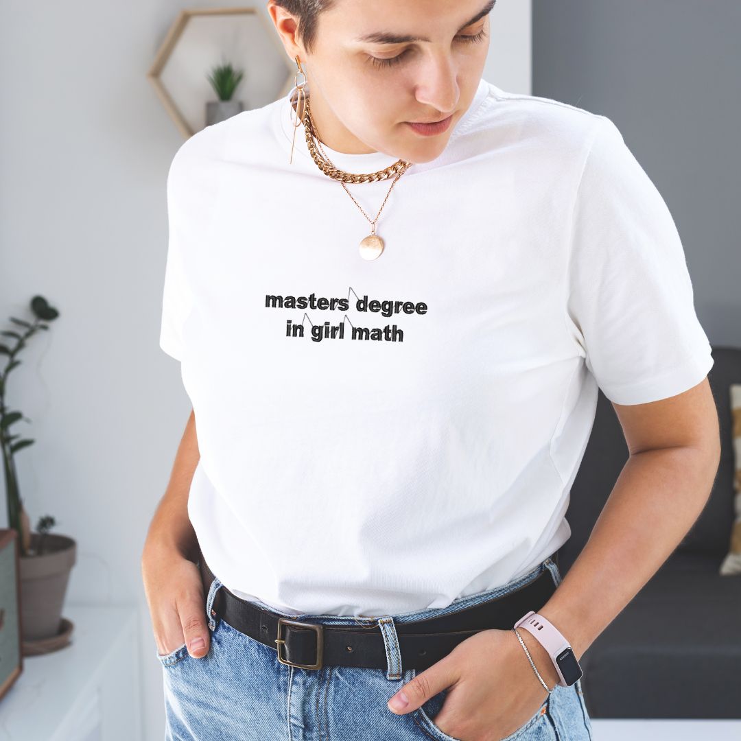 photo lifestyle d'une femme portant un t-shirt à manches courtes blanc avec l'écriture "masters degree in girl math" brodé au centre en noir