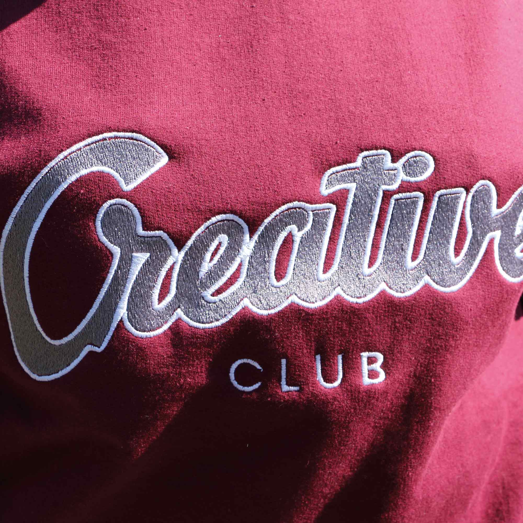 photo gros plan de la broderie creative club sur un crewneck bourgogne