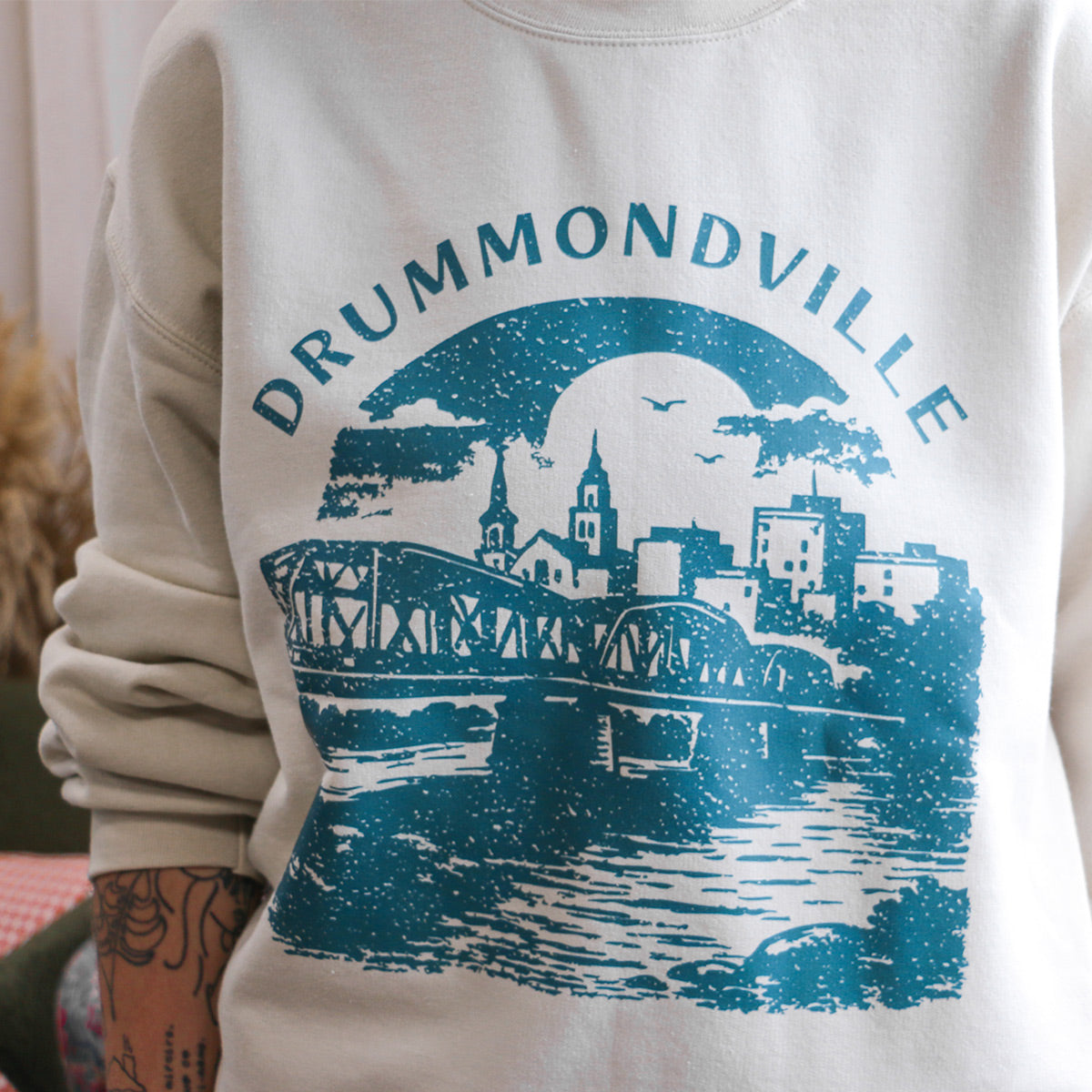 close up du crewneck beige avec l'imprimé "Drummondville et la ville" au centre avec un effet délavé, retro