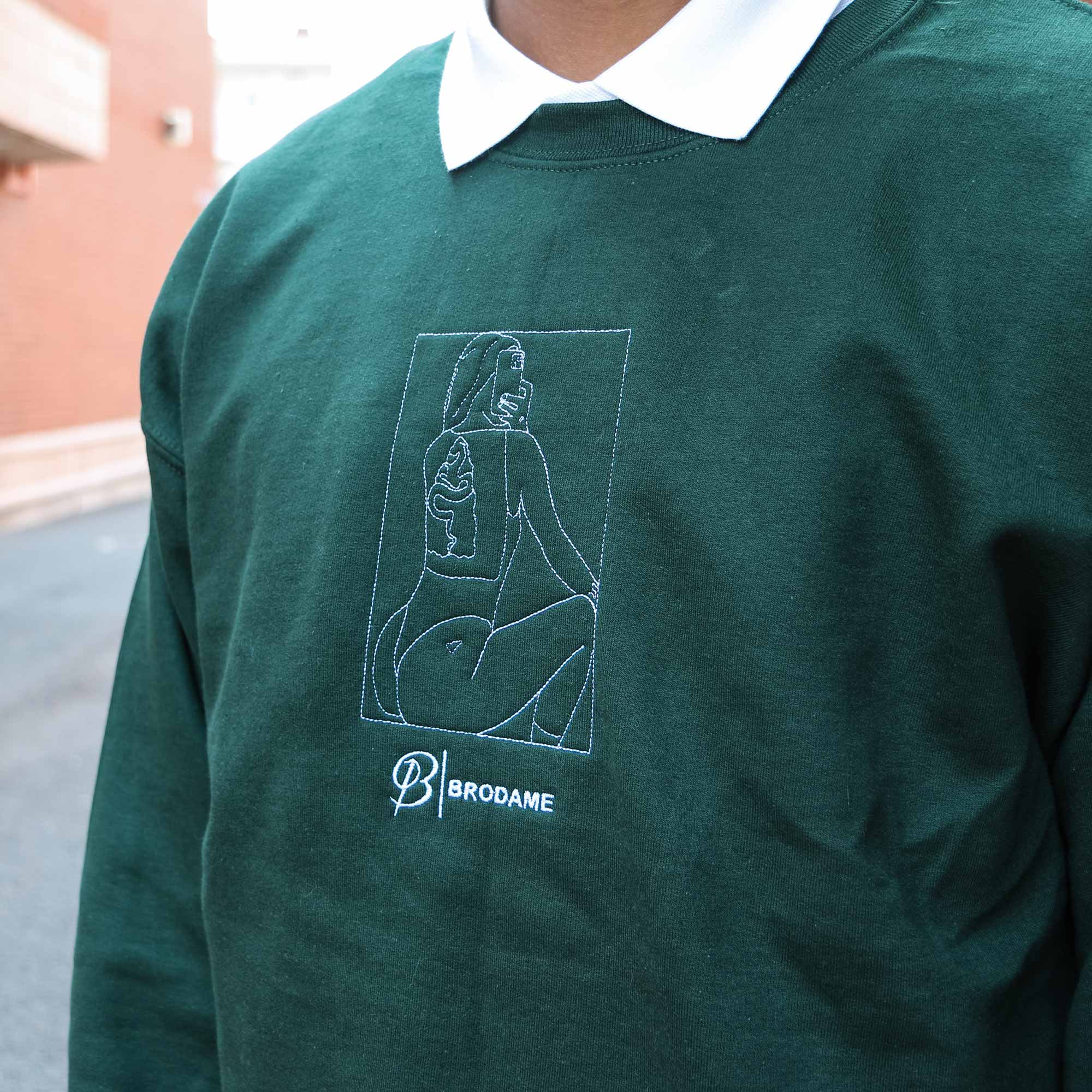 photo gros plan d'un jeune homme portant un crewneck vert foret avec la silhouette coquine de sa copine brodée en blanc