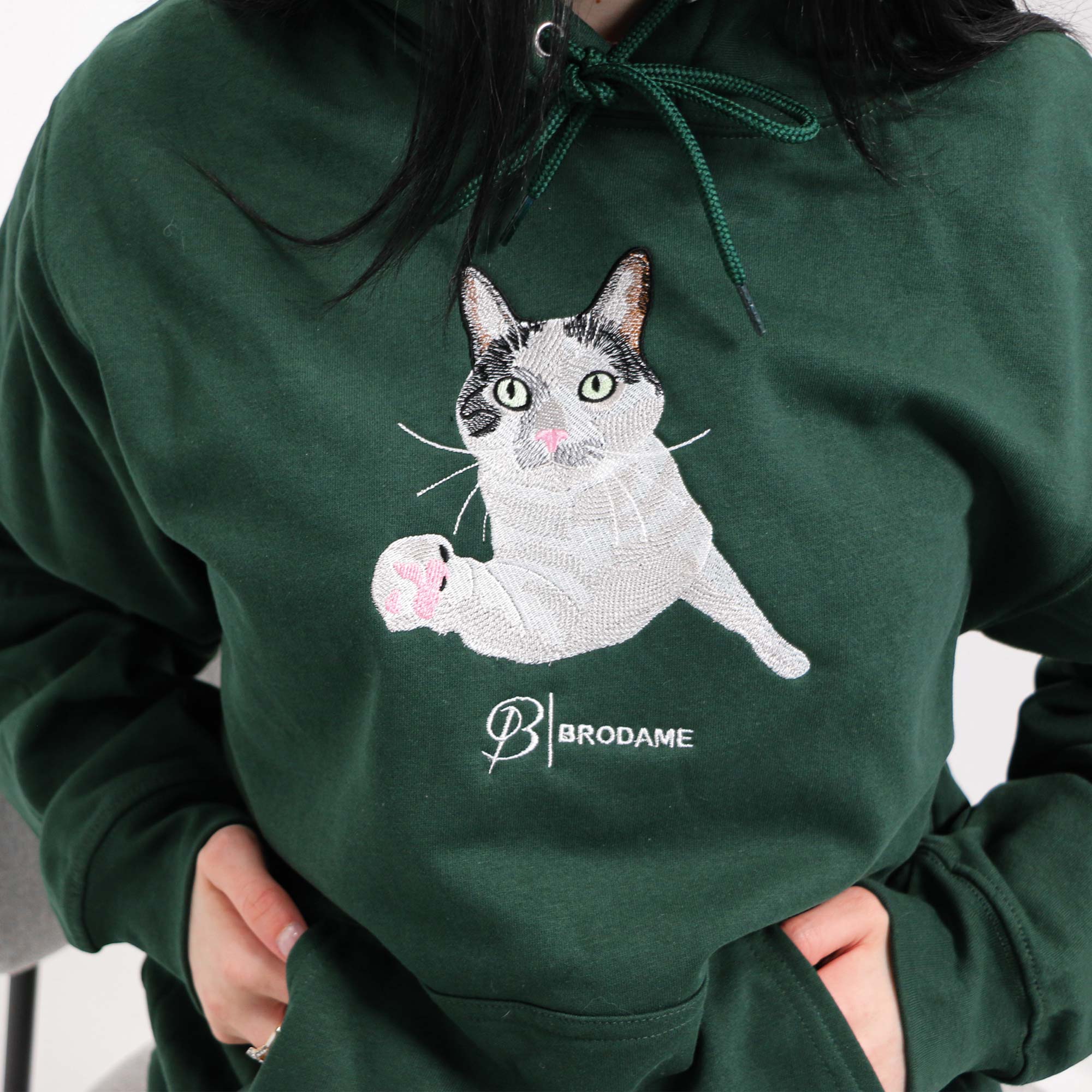 photo plan rapproché d'un coton ouaté à capuchon vert forêt avec une broderie réaliste d'un chat