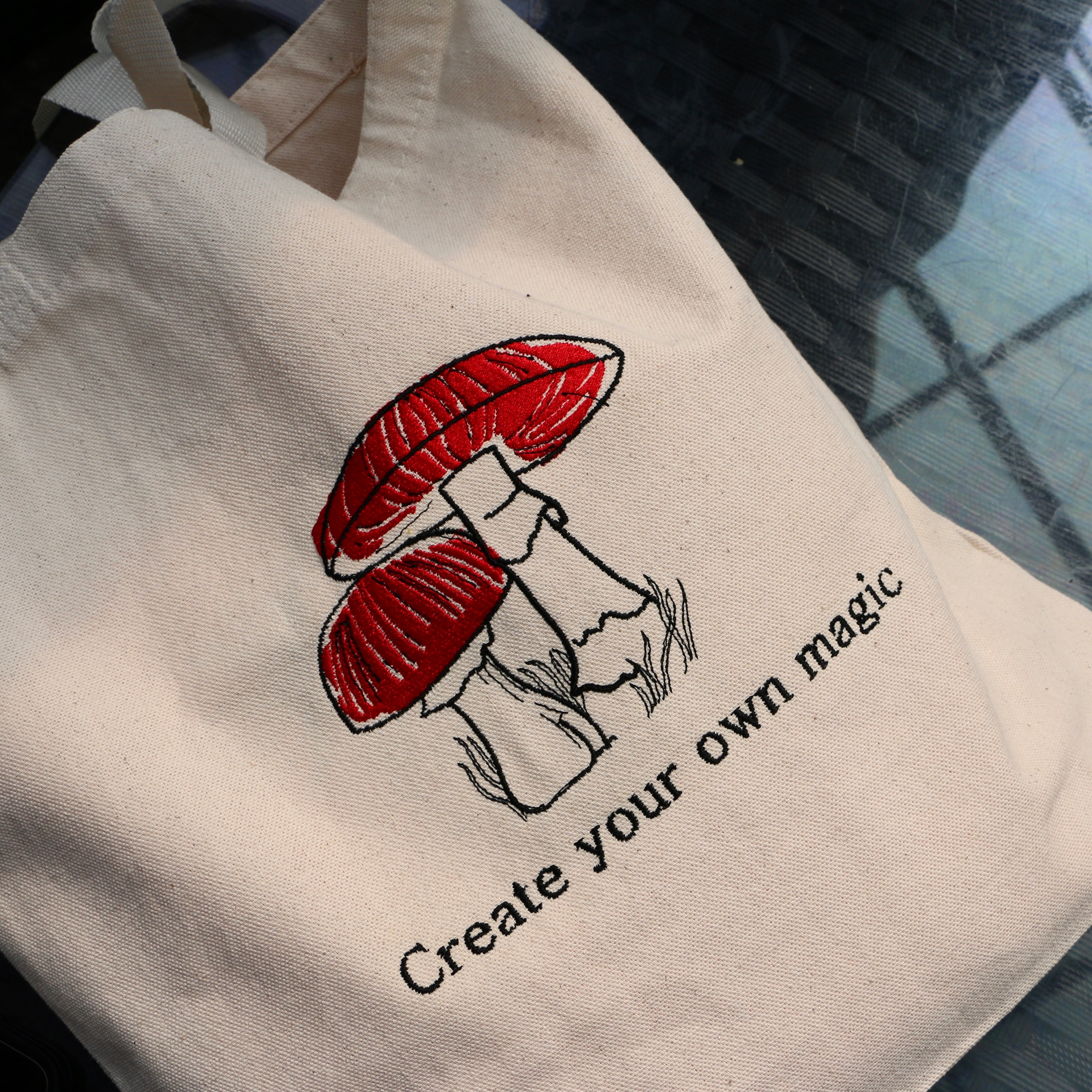 tote bag sac fourre-tout beige photo de proche avec des champignons et une phrase inspirante brodés en rouge et noir