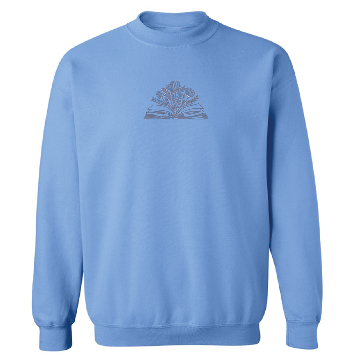 crewneck bleu pâle brodé avec un livre et des fleurs minimalistes en lilas