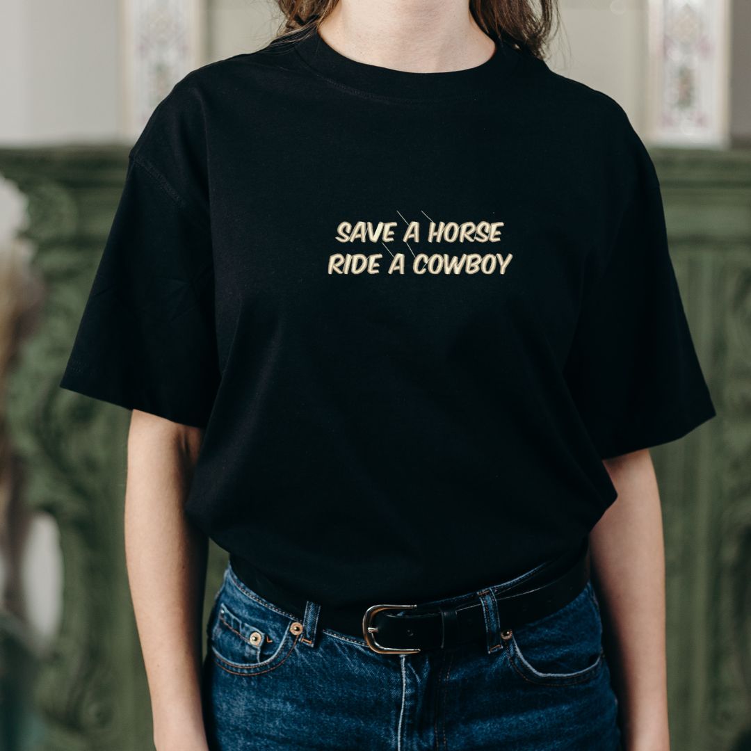 photo lifestyle d'une jeune femme blanche portant un t-shirt noir brodé "save a horse, ride a cowboy"