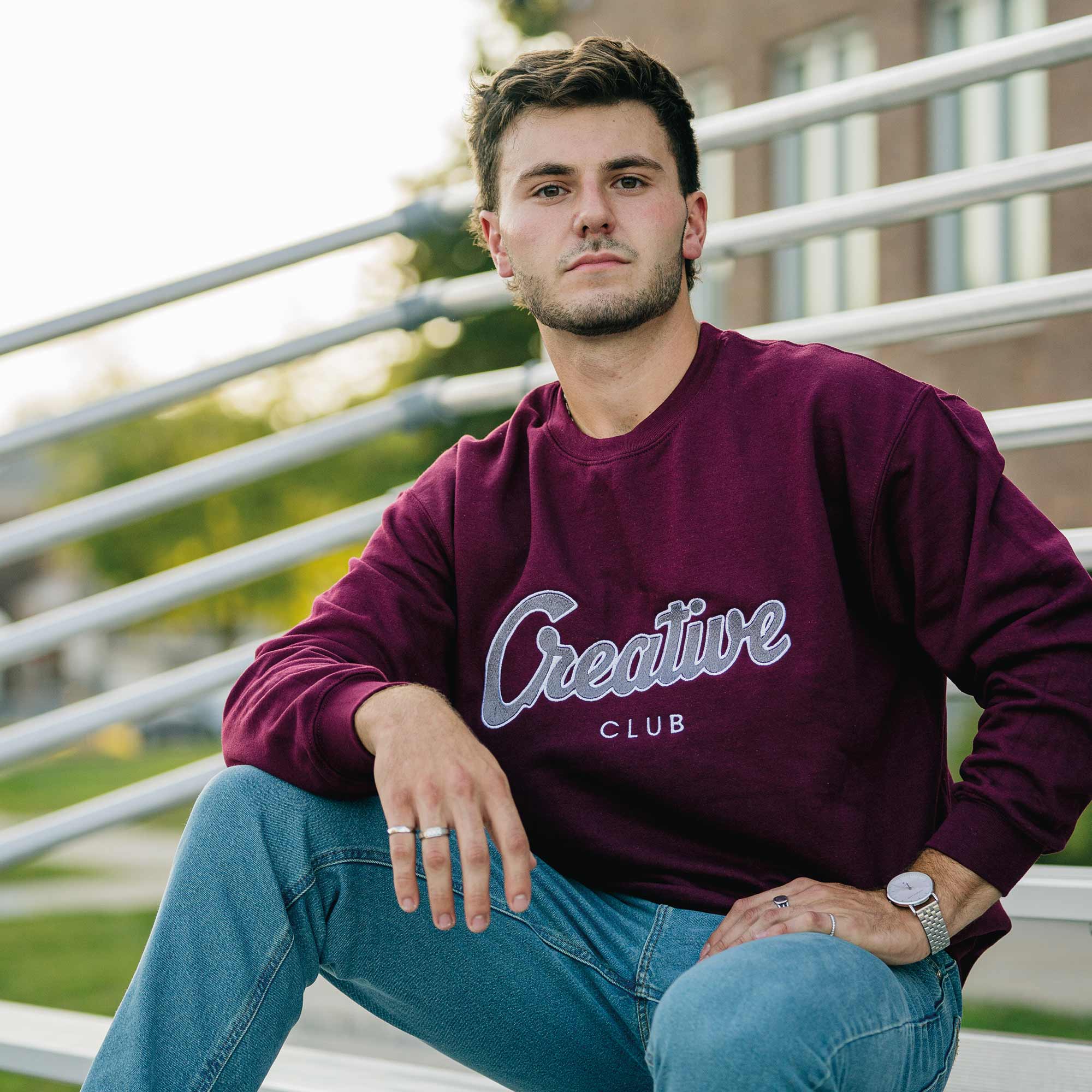 photo d'un jeune homme portant un crewneck bourgogne brodé creative club en gros.