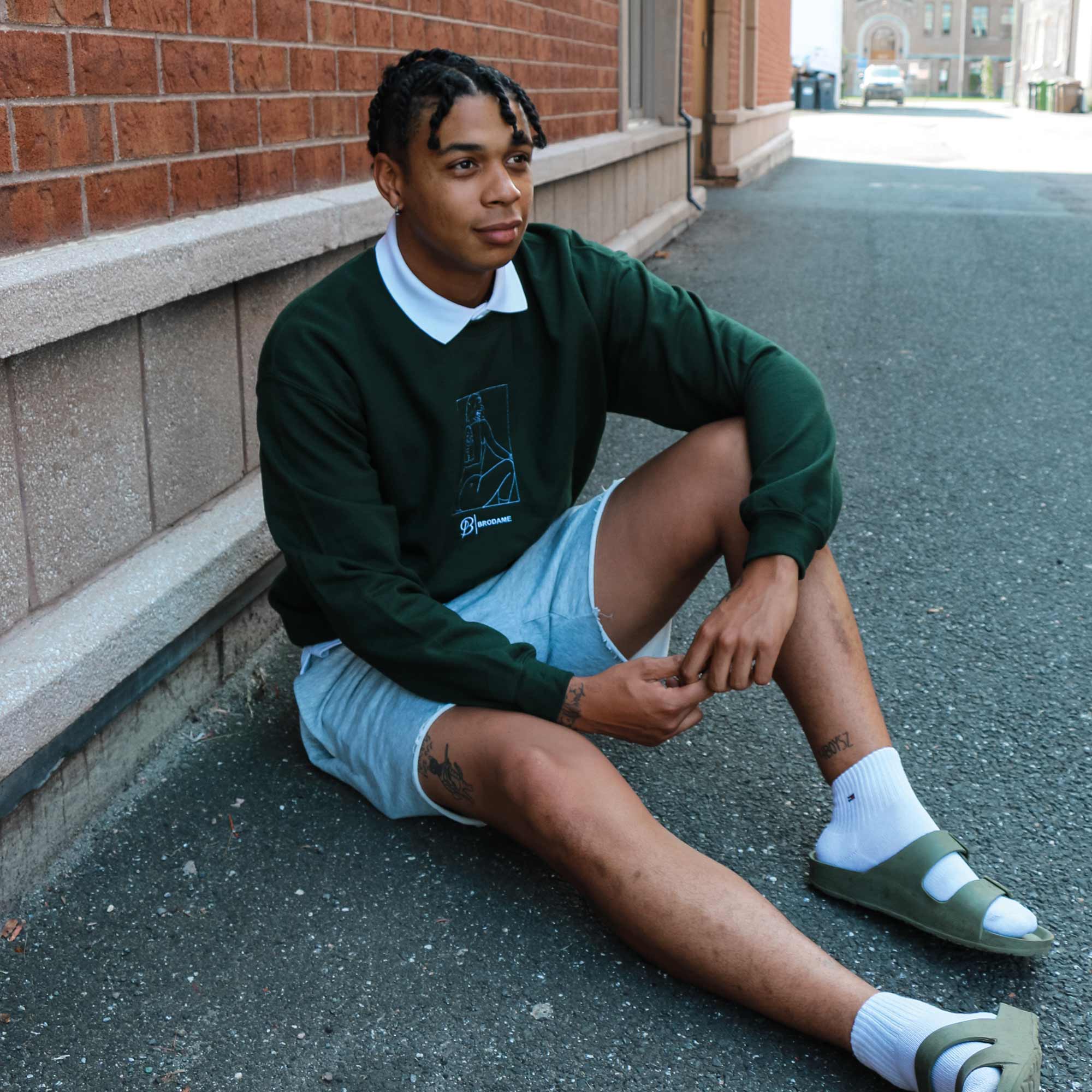 photo lifestyle d'un jeune homme portant un crewneck vert foret avec la silhouette coquine de sa copine brodée en blanc