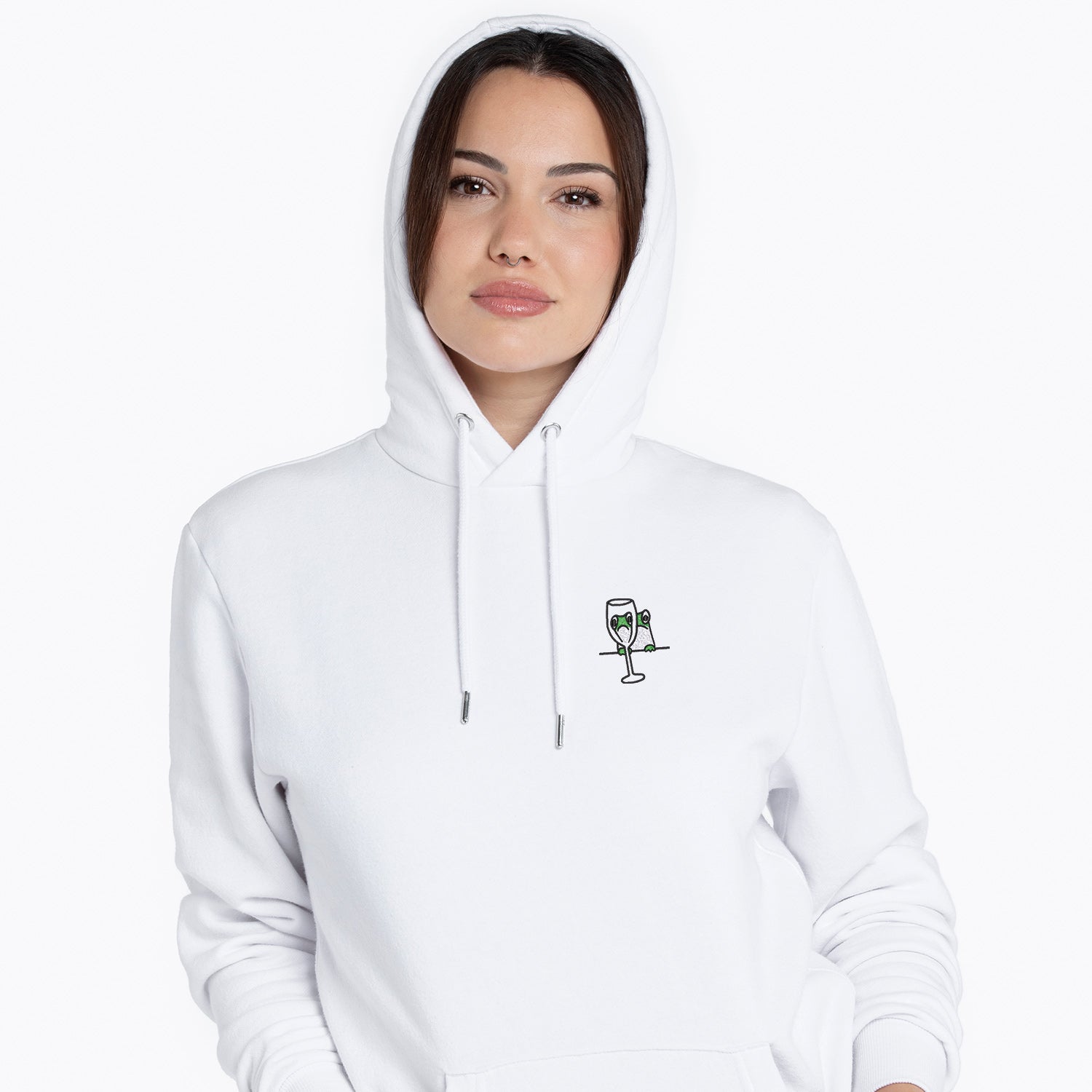 photo lifestyle d'une jeune femme portant un hoodie brodé avec une petite grenouille regardant à travers une coupe de vin