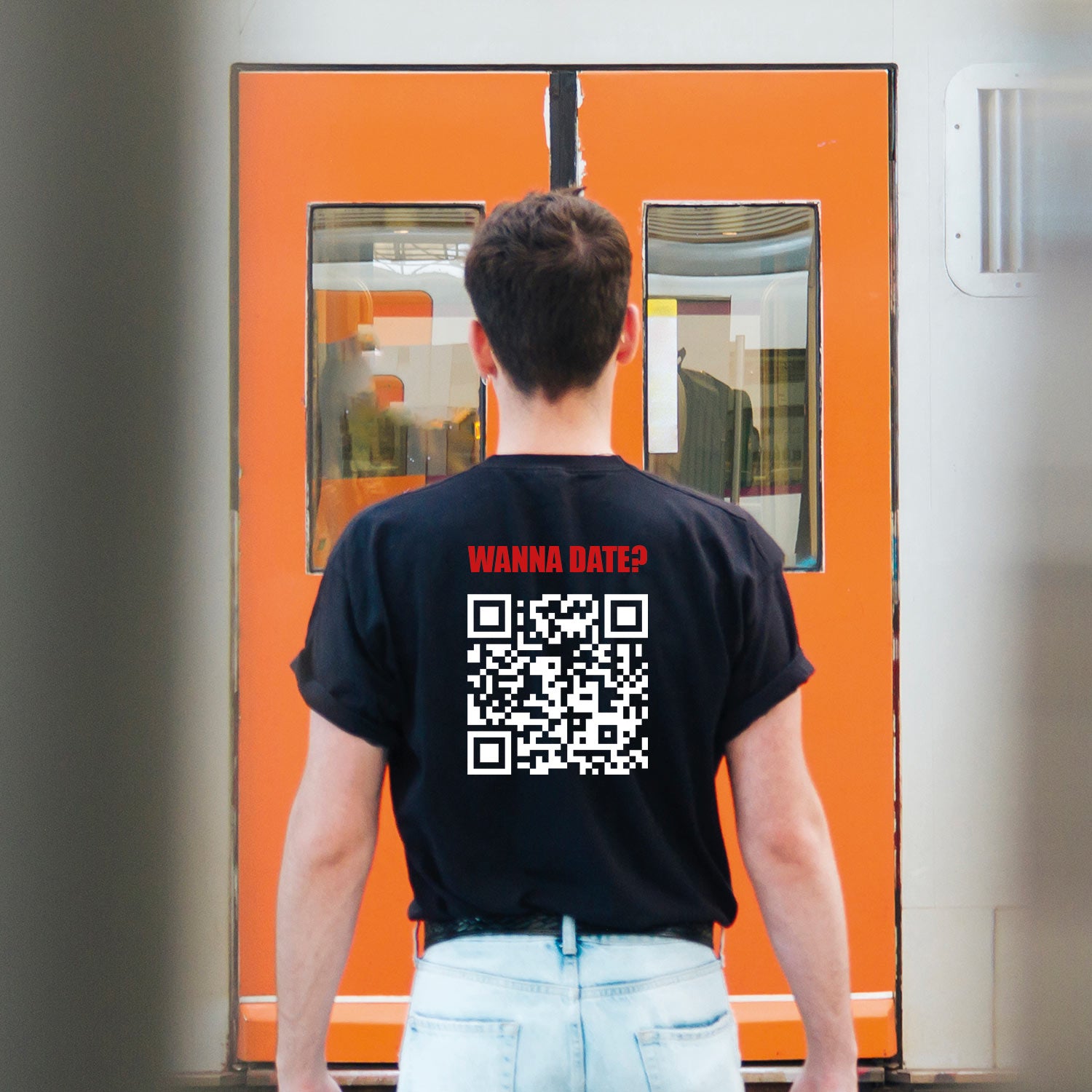 photo lifestyle d'un jeune homme dans une gare de métro portant un t-shirt personnalisé imprimé avec un code qr menant à son profil instagram et la phrase wanna date?