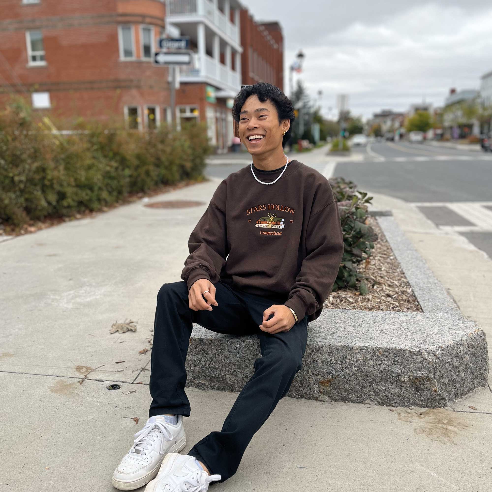 photo lifestyle d'un jeune homme portant un crewneck d'automne stars hollow avec des livres