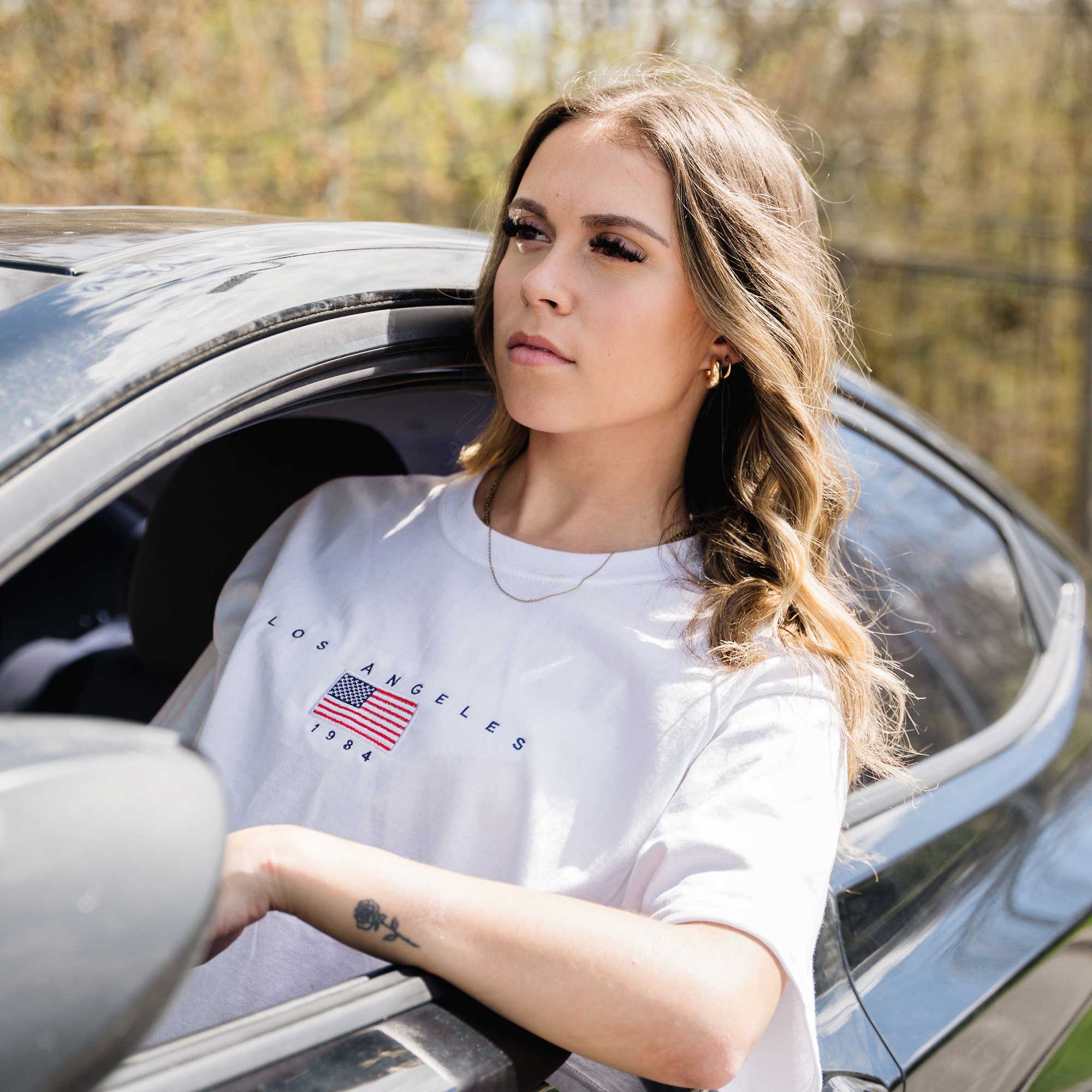 photo d'une jeune femme dans une voiture portant le t-shirt blanc los angeles de brodame