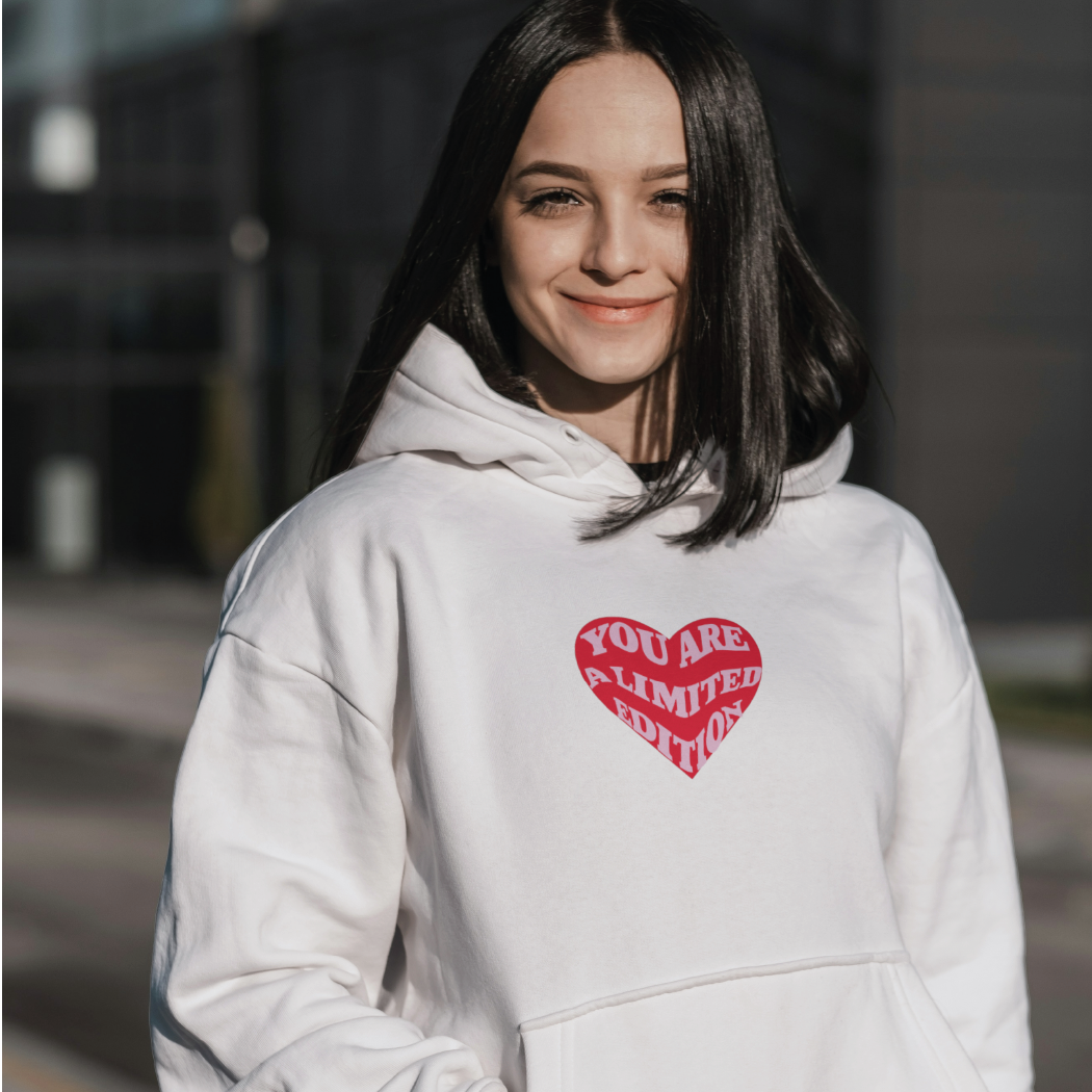 jeune femme portant un hoodie blanc limited edition coeur brodé journée de la femme