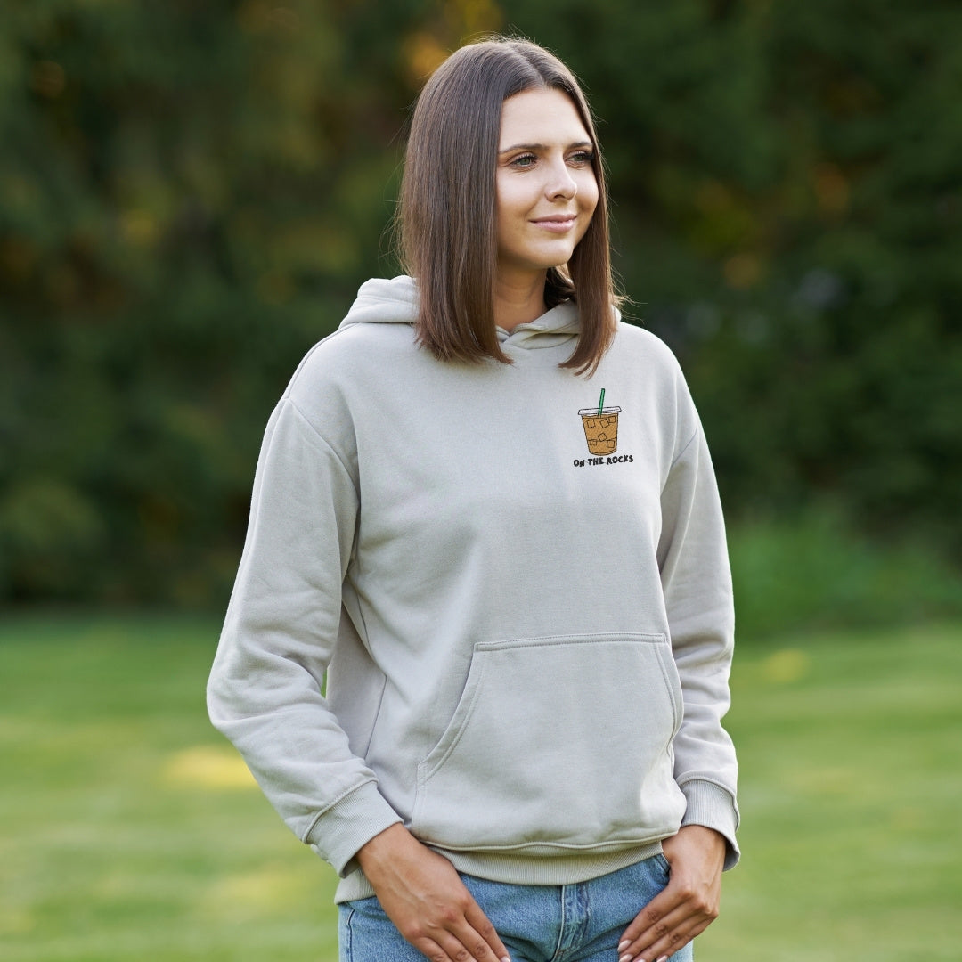 photo d'une jeune femme portant un coton ouaté à capuchon beige avec un café glacé brodé au coeur