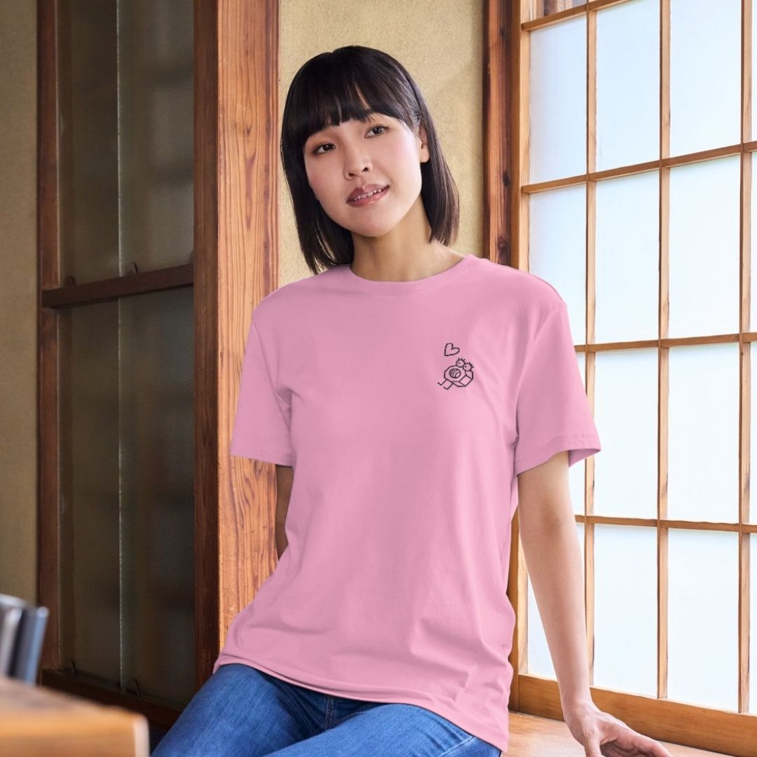 photo d'une jeune femme asiatique portant un t-shirt rose pâle avec une broderie d'écrou et un petit coeur à gauche en noir