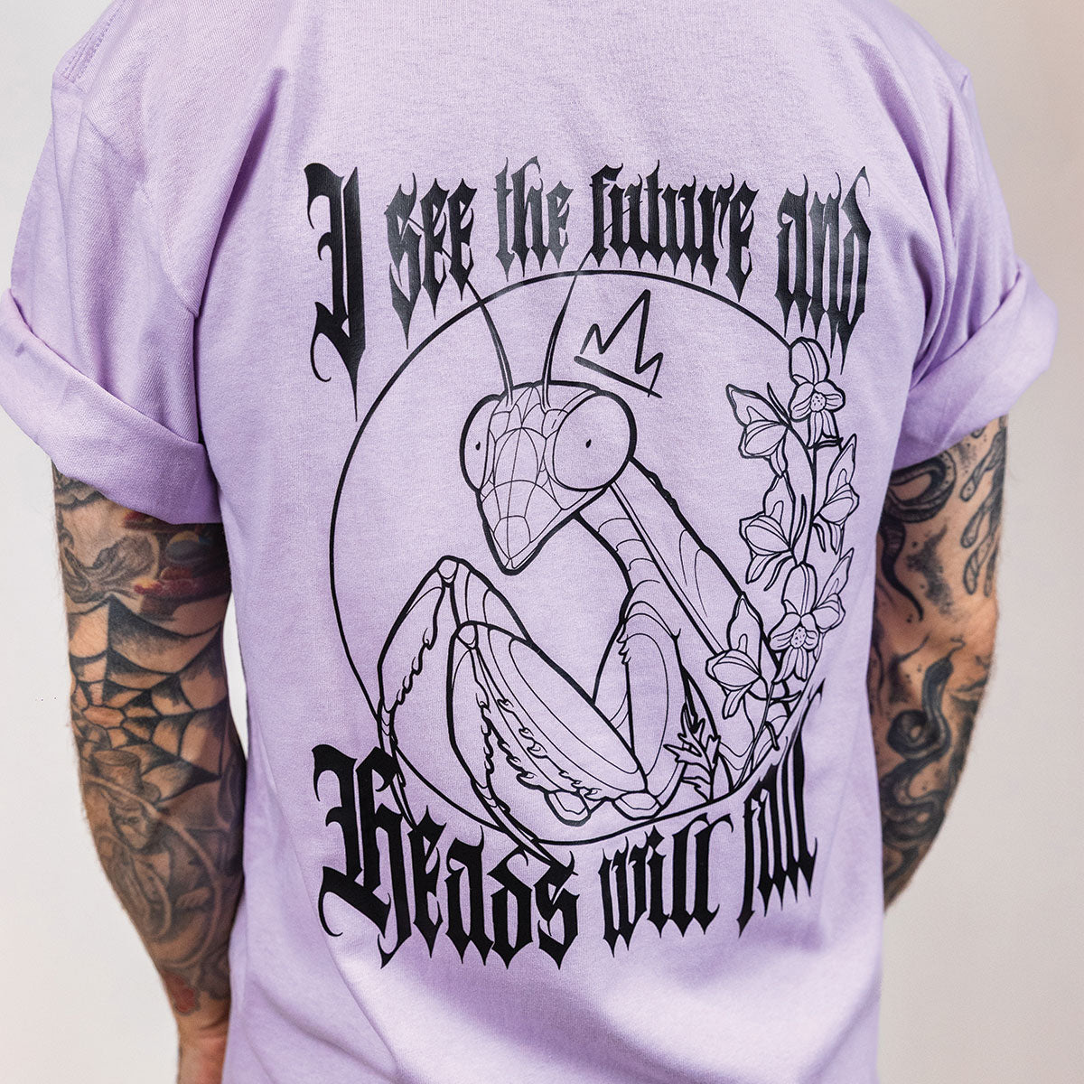 plan rapproché de l'impression noire du dos d'un t-shirt lavande porté par un homme tatoué